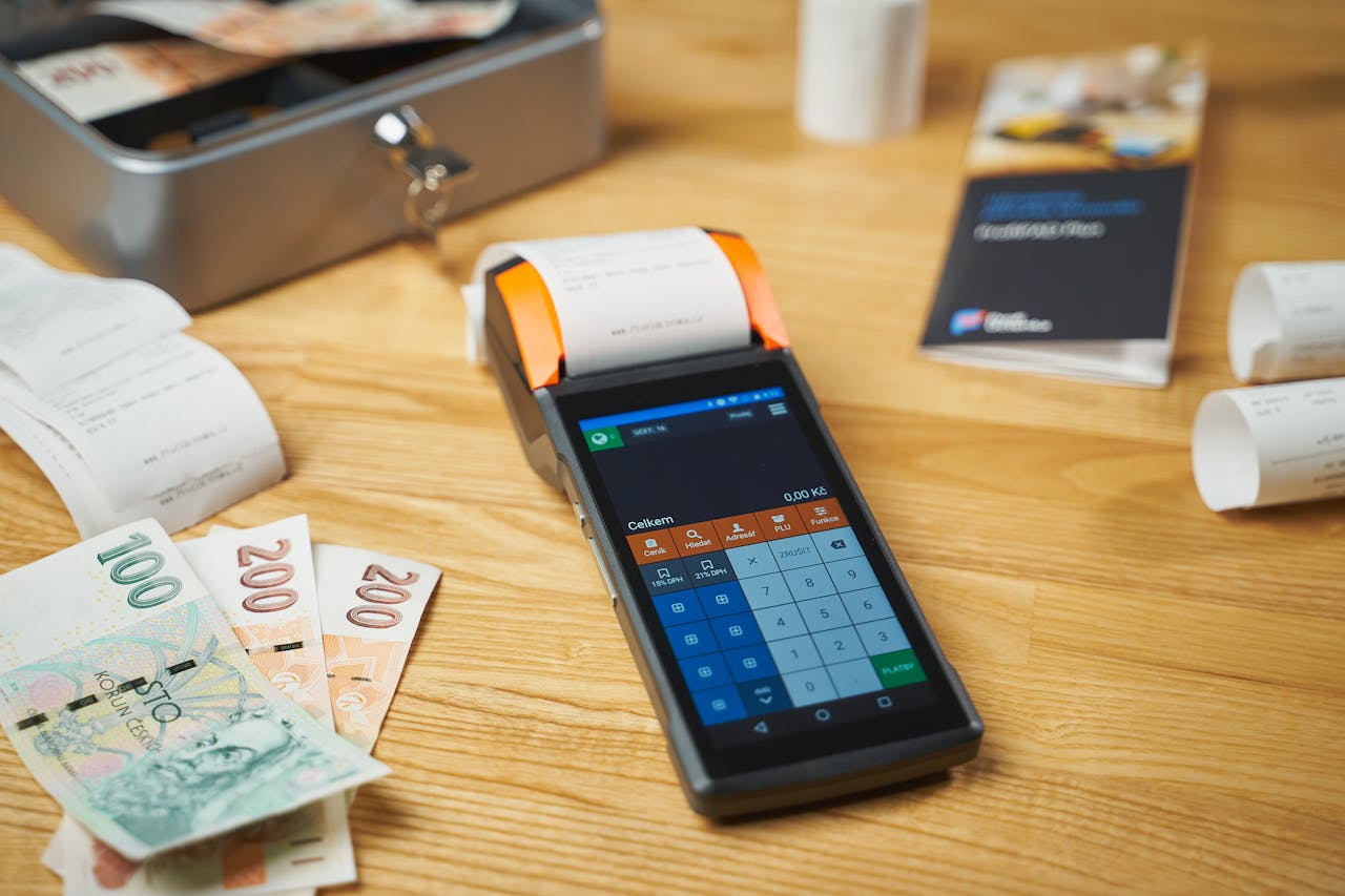 services-01 A modern digital payment terminal on a wooden desk with cash and receipts.